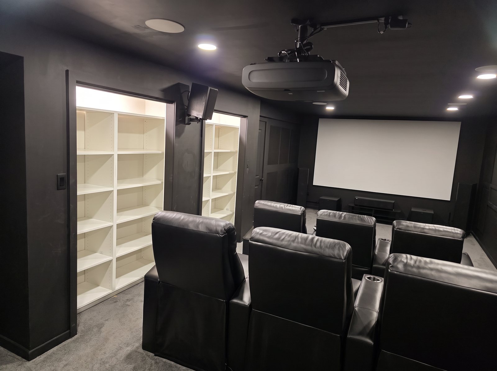Basement home theater with built-in white shelving