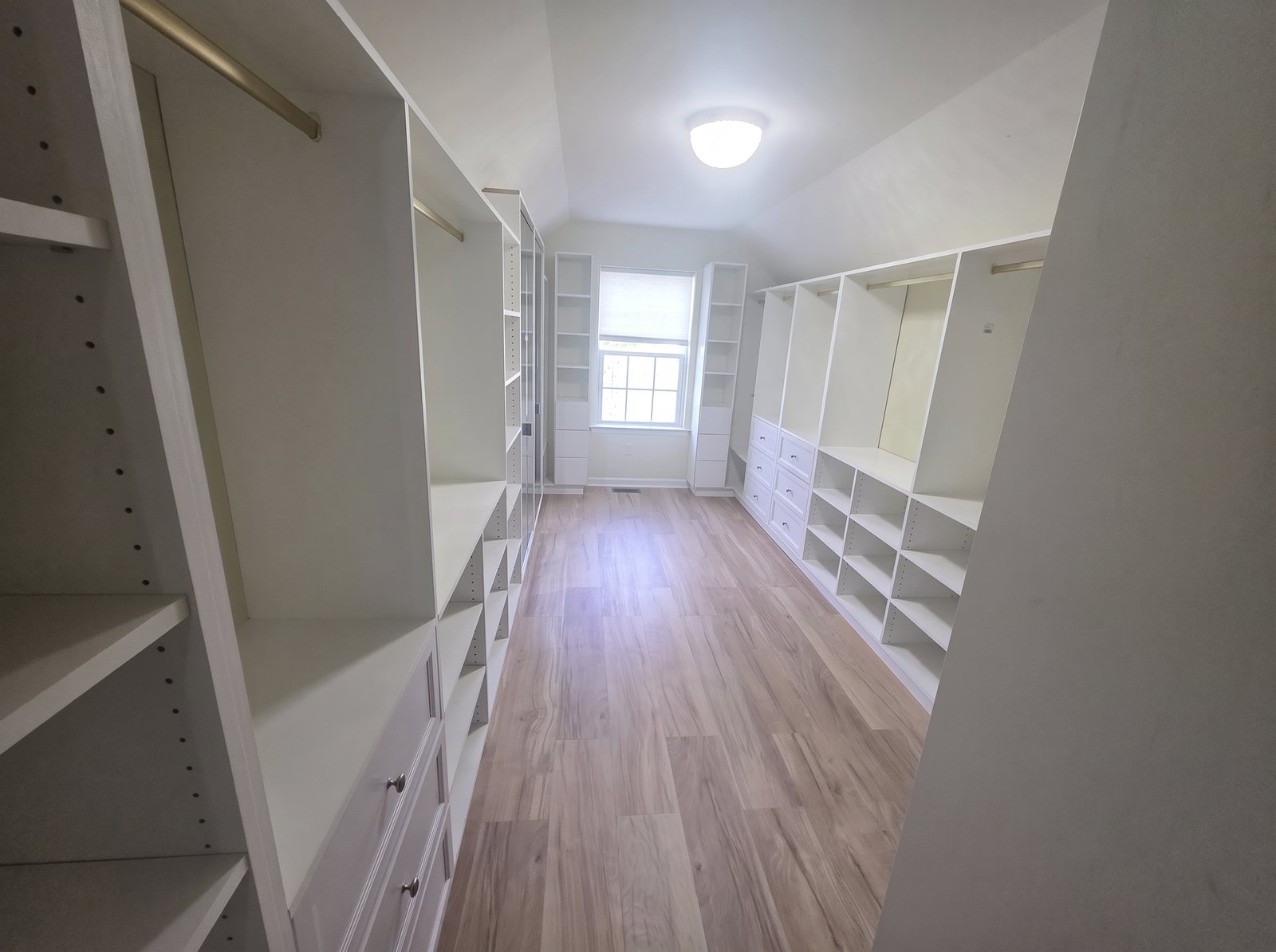 White custom walk-in closet with built-in drawers and shelves on both sides