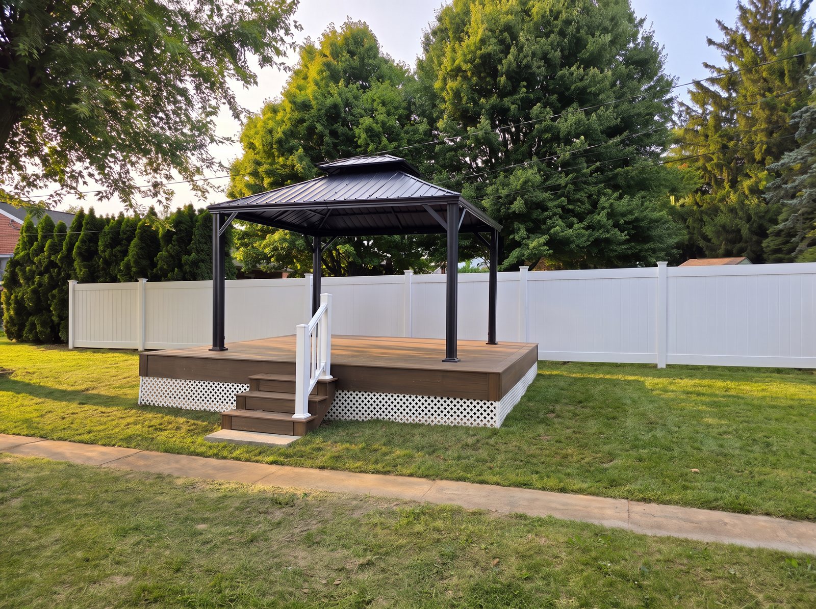Finished brown composite deck with white railing, lattice skirt and a black hardtop gazebo