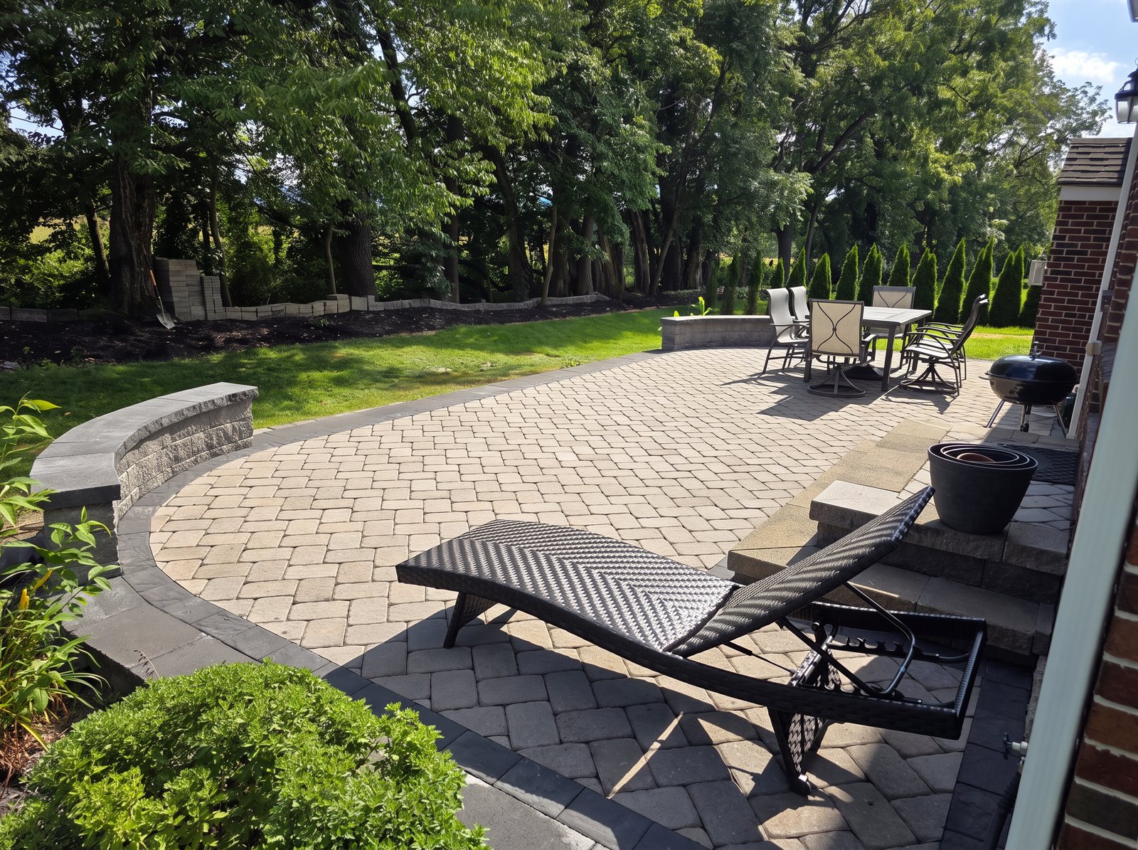 Curved paver patio with a stone seat wall