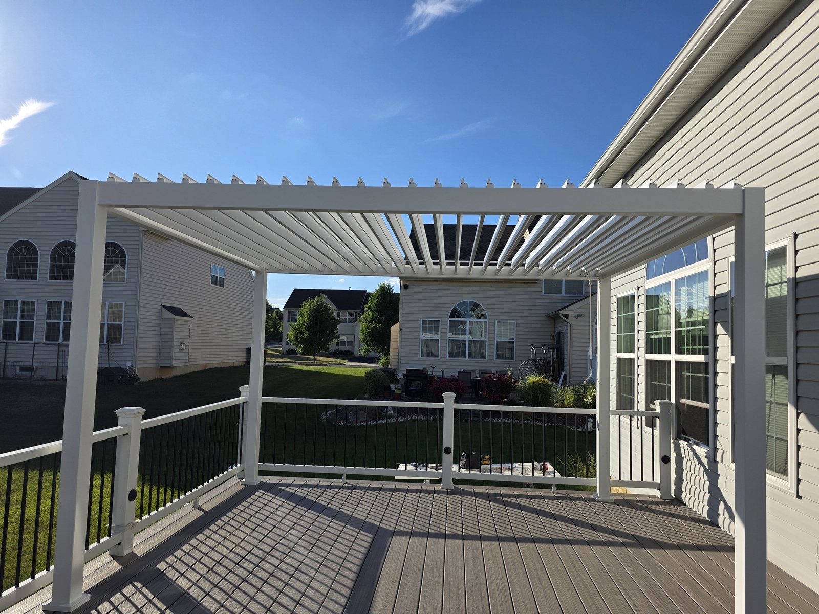 White louvered aluminum pergola on a backyard deck