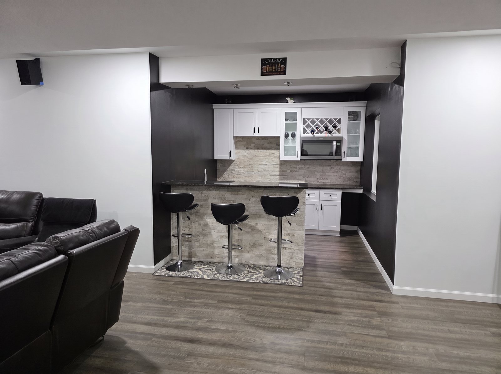 After: the same basement bar with a stone-faced counter and dark accent walls